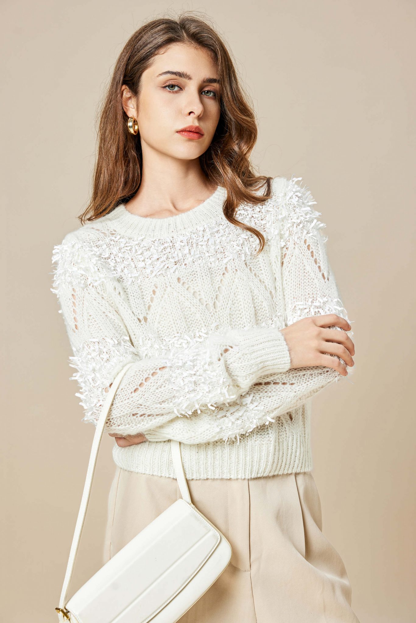 A sophisticated woman wearing a mohair knitted pullover with paper trims, folding her arms