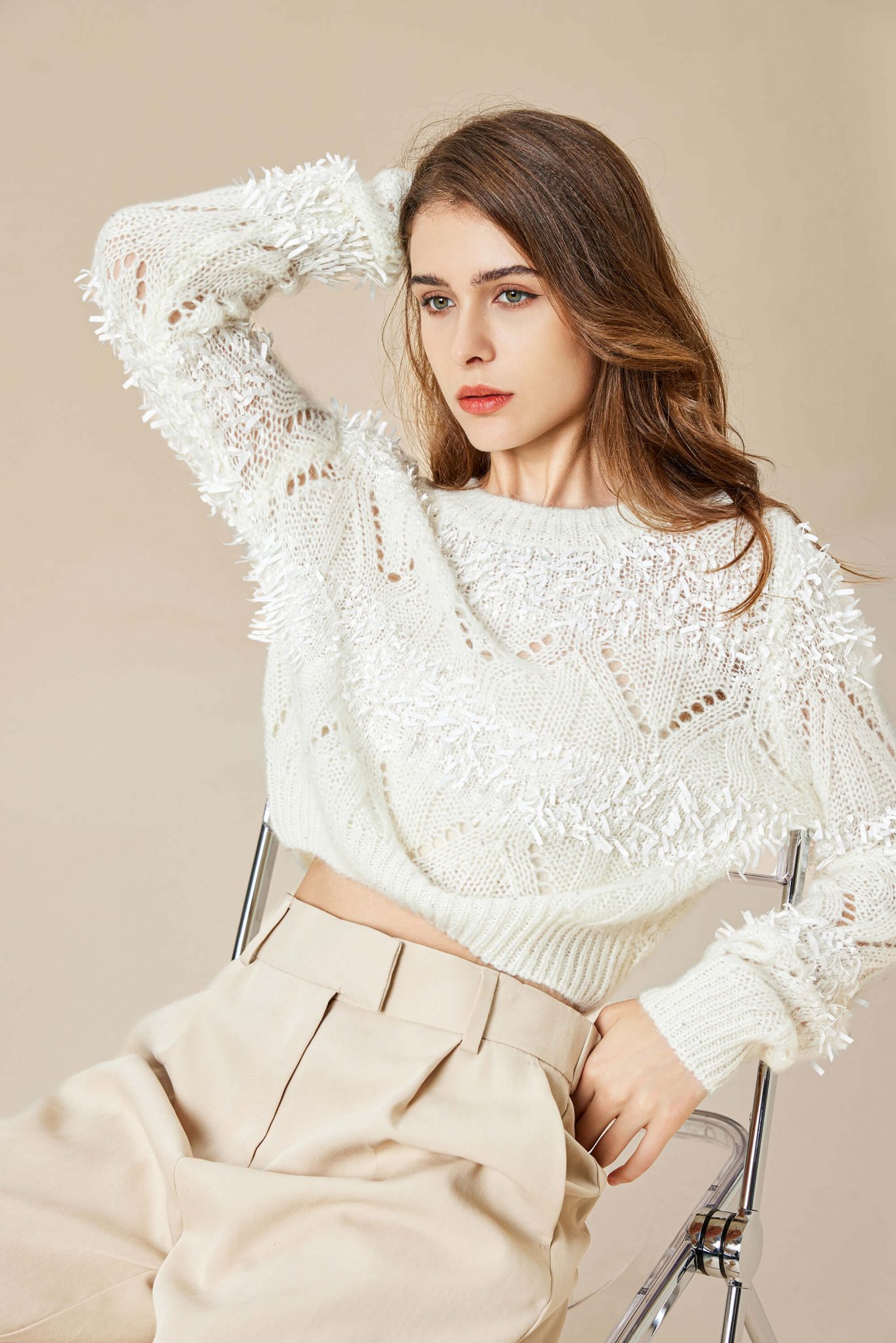 A sophisticated woman wearing a mohair knitted pullover with paper trims, sitting lazily in a chair