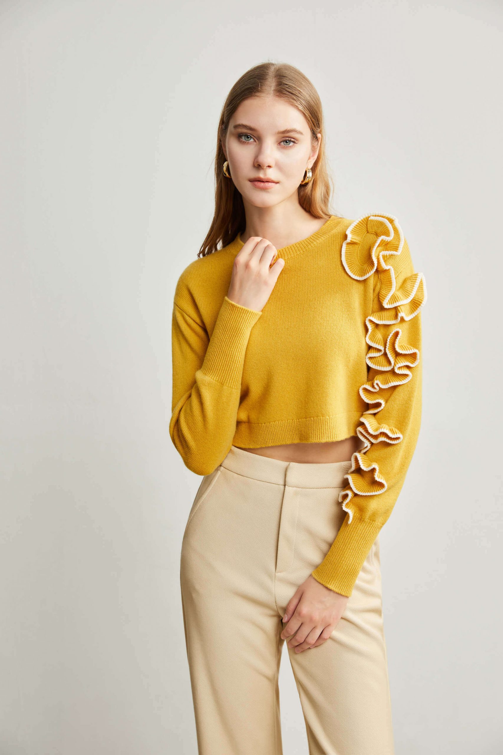 A woman wearing a yellow sweater with small flower decorations