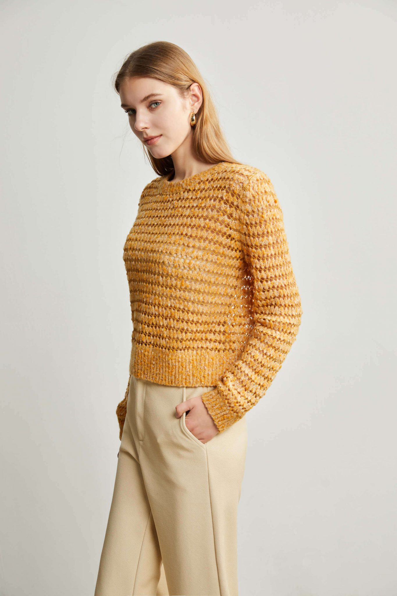 A woman wearing a yellow eyelet stitch sweater