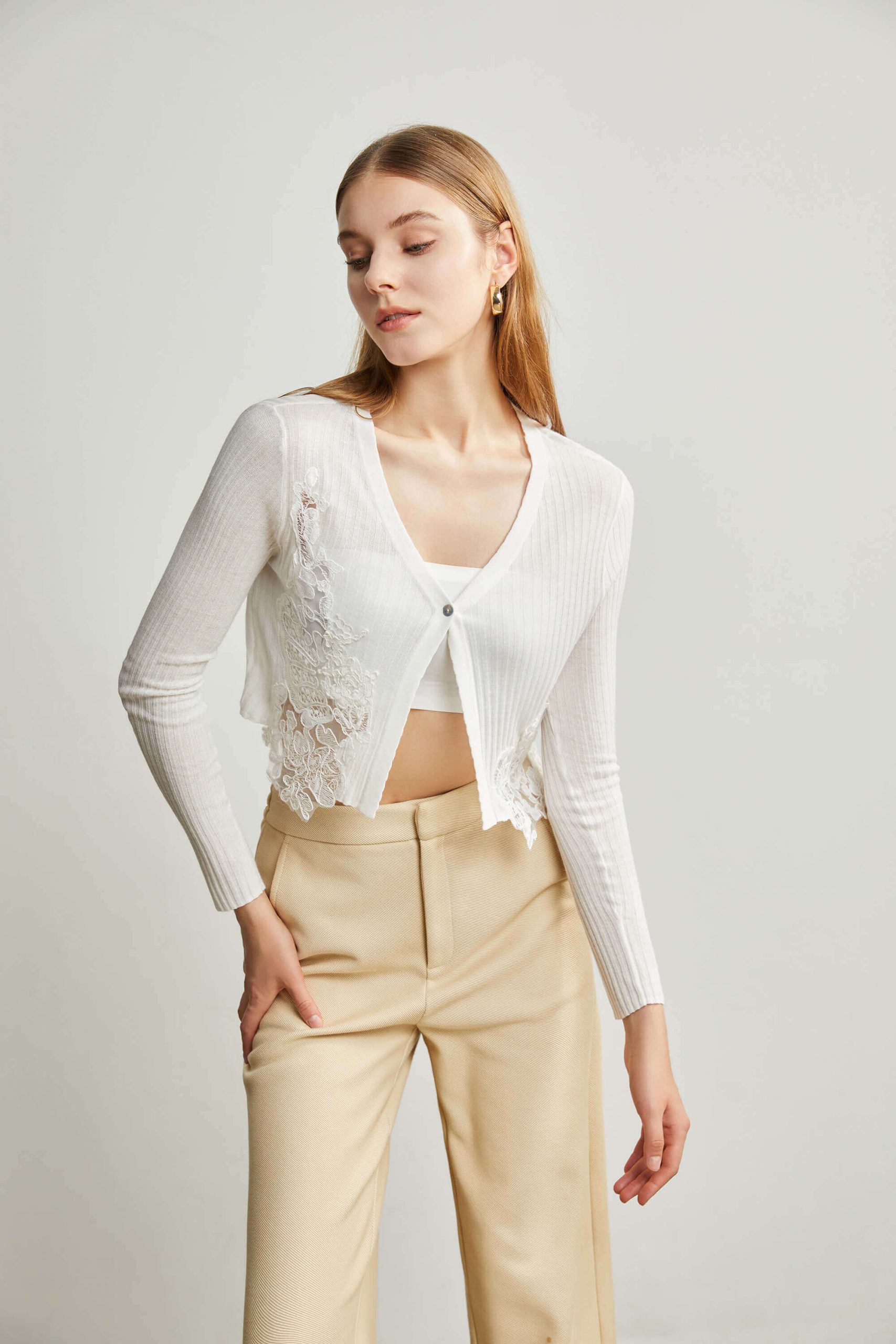 A girl wearing a lightweight cropped single button knit cardigan with light apricot casual pants