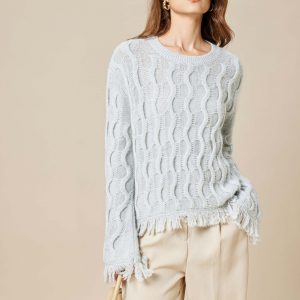 A girl wearing a mohair wool blend Lurex knitted pullover with tassels, holding a bag in her right hand and her left hand in her pocket