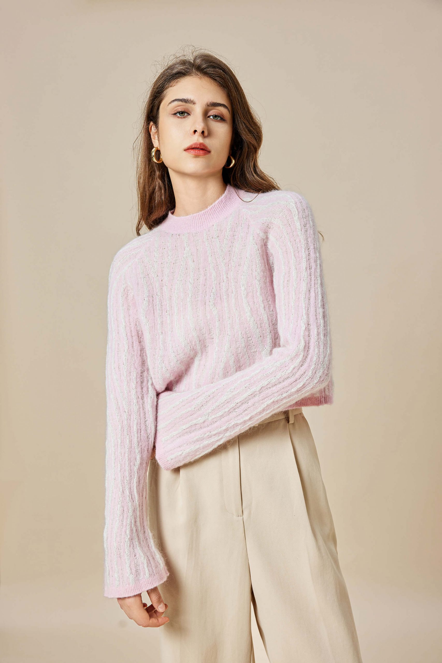 A woman wearing a cropped mock turtleneck sweater with vertical pink stripes, made of a wool and mohair blend